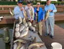 Lake Conroe Fishing Adventures Customers Stand Next to Fillet Table Holding Hybrid Striped Bass on Lake Conroe