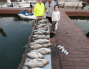 Lake Conroe Fishing Adventures Customers Stand Next to Fillet Table Holding Hybrid Striped Bass on Lake Conroe