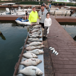 Lake Conroe Fishing Adventures Customers Stand Next to Fillet Table Holding Hybrid Striped Bass on Lake Conroe