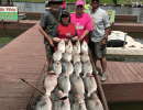 Lake Conroe Fishing Adventures Customers Stand Next to Fillet Table Holding Hybrid Striped Bass on Lake Conroe