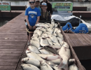 Lake Conroe Fishing Adventures Customers Stand Next to Fillet Table Holding Hybrid Striped Bass on Lake Conroe