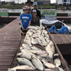 Lake Conroe Fishing Adventures Customers Stand Next to Fillet Table Holding Hybrid Striped Bass on Lake Conroe